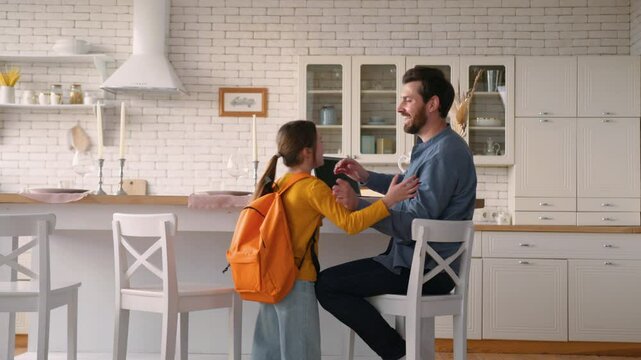 Carefree little Caucasian daughter girl kid run return home from school lessons carrying backpack education father guy man meeting child schoolgirl talk conversation male dad parent family cuddle kiss