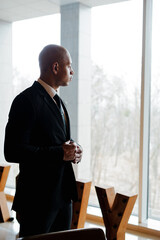 African american businessman standing looking at window in office 