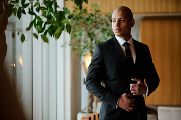 Elegant african american businessman in formal attire standing in office hall