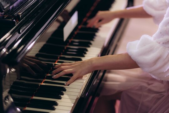 Closeup woman's hand playing piano. Favorite classical music. Top view with dark vignette.