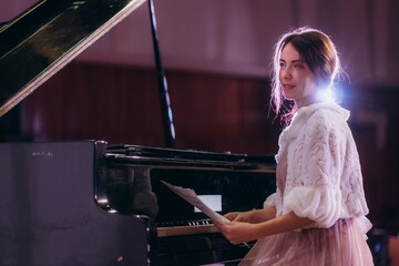 Close up of woman's hands playing piano by reading sheet music. Selective focus