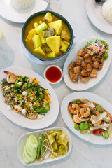Delicious assortment of traditional meals in the south of Thailand. Yellow curry fish bamboo shoot and green taro, stir-fried shrimp paste, deep fried crispy pork belly, stir fried stinky vegetables.