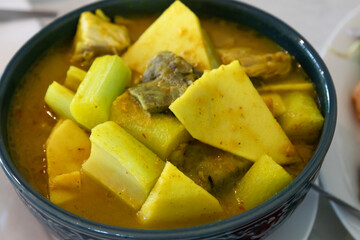 Yellow curry with fish, bamboo shoot and green taro (aaw dip) Thai Southern style food on wooden table.