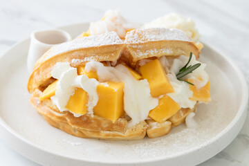 Delicious waffle mango dessert with young coconut and whipped cream.