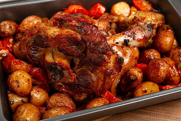 Pork knuckle, baked with vegetables, new potatoes , on a baking sheet, homemade, no people,