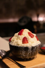Shaved ice dessert with sweet strawberry toppings, Strawberry Bingsu. (Frozen milk spinning to snow flake and topped with fruits and syrup)