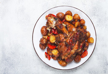 Pork knuckle baked with vegetables, new potatoes , on a white plate, homemade, no people,