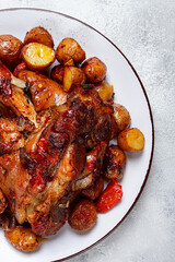 Pork knuckle baked with vegetables, new potatoes , on a white plate, homemade, no people,