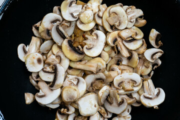 Close-up of mushrooms sautéing in a skillet, golden-brown with a hint of olive oil, creating a rustic and flavorful culinary vibe.