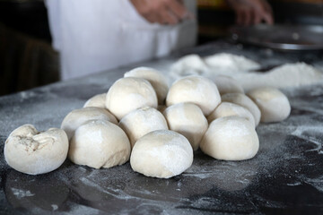 Freshly prepared dough balls on a kitchen surface.