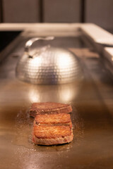 Grilled meat sizzling on a hot plate.