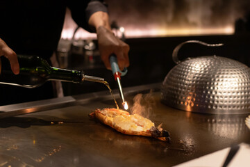 Chef flambeing dish with torch and alcohol.