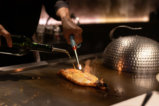 Chef flambeing dish with torch and alcohol.