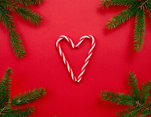 Christmas banner, love xmas symbol, holiday concept card, candy canes and fir  tree branches on red background.