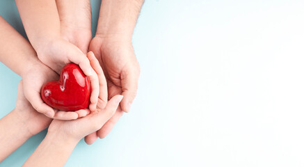 Heart day concept, red heart in family memebers hands top view empty space background.Healthcare. Cardiology. Health protection.