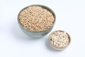 Oat grains and flakes in bowls isolated on white