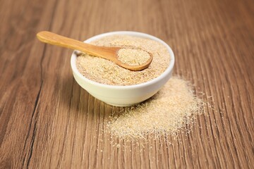 Oat bran in bowl and spoon on wooden table, closeup