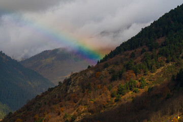 Arco iris saliendo detrás de ladera de montaña
