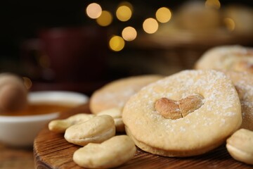 Tasty cashew cookies with powdered sugar on table, closeup. Space for text