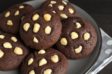 Delicious chocolate cookies with hazelnuts on black table, closeup