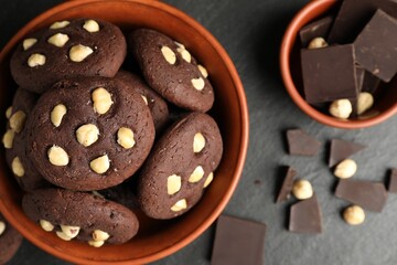 Tasty chocolate cookies with hazelnuts on black table, flat lay