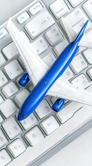 A model airplane is placed on a computer keyboard, featuring a blue and white design. This setup suggests a creative workspace for aviation enthusiasts or model makers