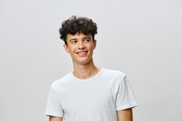 Young man smiling in casual white t shirt, joyful expression, light grey background, modern lifestyle, confidence, youth, happiness, attractive features, relaxed pose, natural beauty, emotions