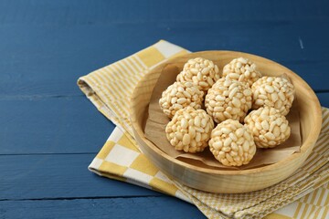 Tasty puffed rice balls on blue wooden table, closeup. Space for text