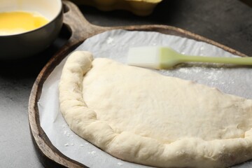 Uncooked calzone pizza on grey table, closeup