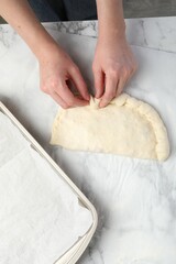 Woman making calzone pizza at table, top view