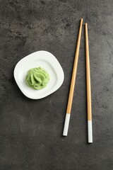 Hot wasabi paste and chopsticks on grey textured table, top view