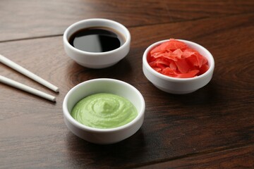 Hot wasabi paste, soy sauce, ginger and chopsticks on wooden table, closeup