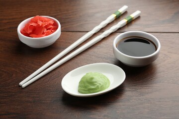 Hot wasabi paste, soy sauce, ginger and chopsticks on wooden table, closeup