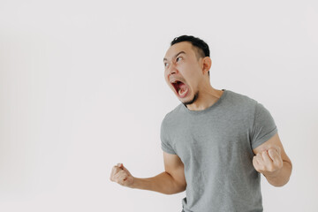 Angry and furious shouting face of Asian man in grey t-shirt isolate on white.