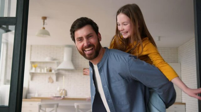 Joyful Caucasian family happy little daughter child playing funny game with parent man dad schoolgirl laugh pretend airplane fly at home. Guy father male holding girl kid piggyback ride fooling around