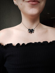 Black agate gemstone with blue inserts choker. Black irregular cord beaded necklace on woman's neck...