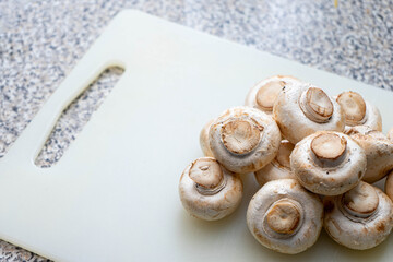 White mushrooms on a silicone cutting board, ready for preparation.