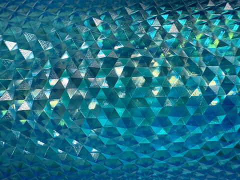 Close up of beautiful shimmering reflective geometric triangular snake skin crystal texture in blue aquamarine or teal or tosca color. Deep blue tosca color geometrical seamless texture.