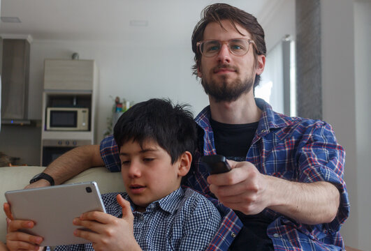 Father and son bonding with tablet and TV remote at home