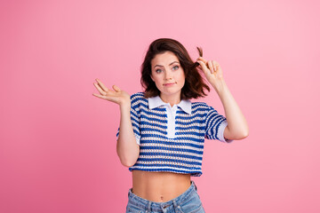 Charming young woman with a playful expression wearing a striped knit polo on pink background