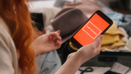 Unrecognizable traveler woman at bedroom holding mobile phone red screen sms message notification airline cancelled flight cancel problem female girl preparing trip travel trouble tickets passport
