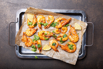  Fried shrimps with lemon and green on a metal tray, top view close up