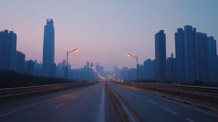 Fototapeta premium A serene urban landscape at dawn with a wide road and towering buildings in the background.