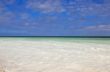 Obraz premium panorama with the light white sea turning into deep blue and clouds in the pale blue sky