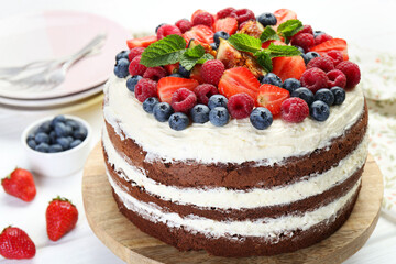 Delicious chocolate sponge cake with berries served on light table, closeup