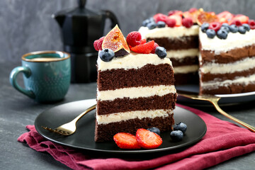 Piece of delicious chocolate sponge cake with berries served on black table, closeup