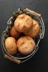 Metal basket with homemade tasty buns on black textured table, top view