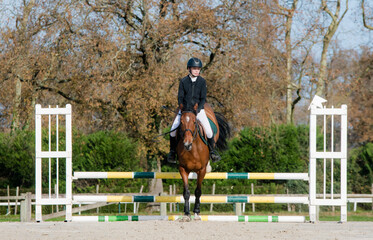 Beautiful young rider on her mare with her protective vest during a show jumping competition
