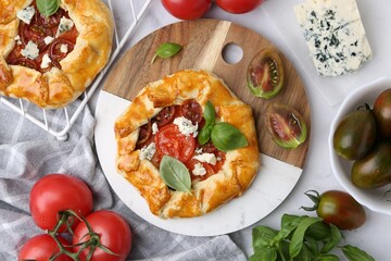 Tasty galettes with tomato, basil and cheese on white marble table, flat lay