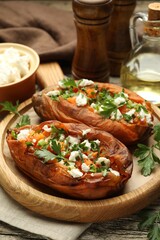 Tasty cooked sweet potatoes with feta cheese, green onion and parsley on table, closeup